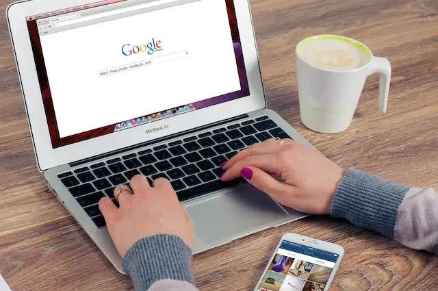 Hands on the keyboard typing a search on Google.