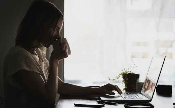 women-holding-cup-looking-toword-laptop